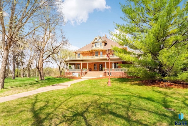 rear view of property featuring brick siding, a porch, and a yard