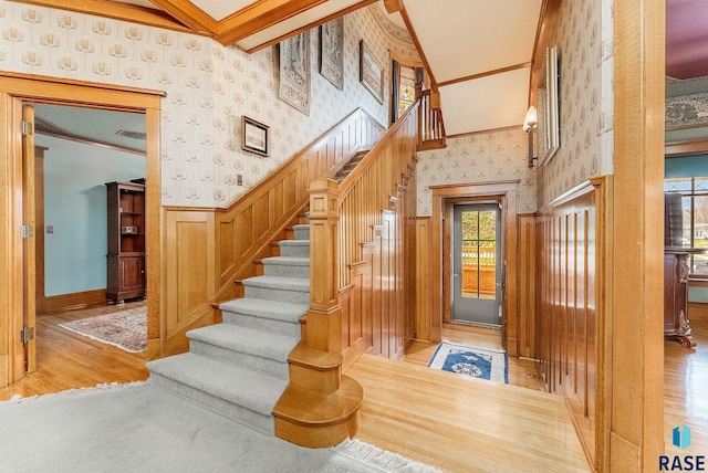 stairs featuring crown molding, wallpapered walls, and wood finished floors