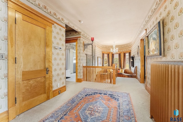 hallway with an inviting chandelier, carpet, and wallpapered walls