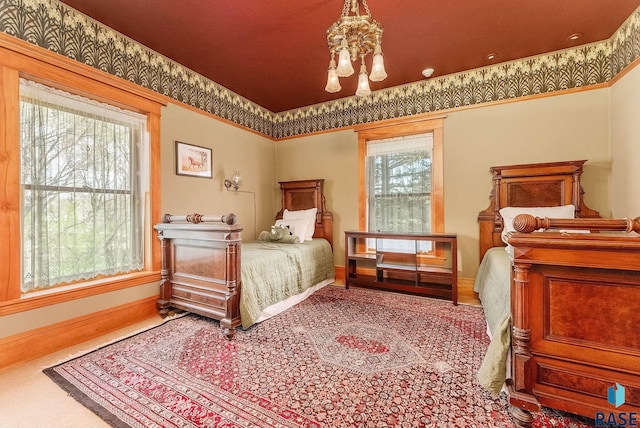 carpeted bedroom featuring baseboards, a chandelier, and crown molding