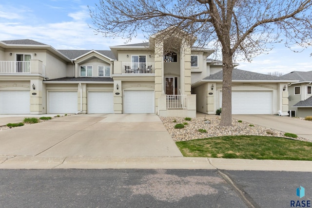 view of front of property featuring driveway, a garage, stucco siding, and a balcony