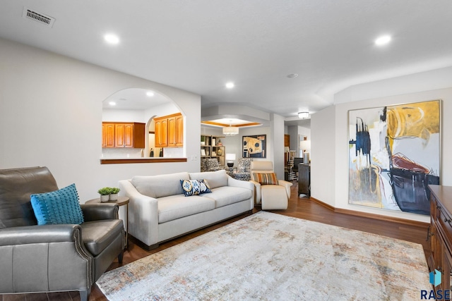 living area with dark wood-style floors, recessed lighting, visible vents, baseboards, and arched walkways