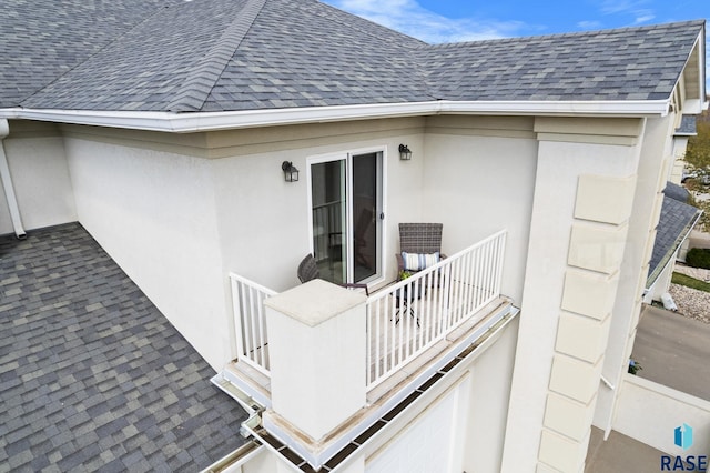 entrance to property with stucco siding, roof with shingles, and a balcony