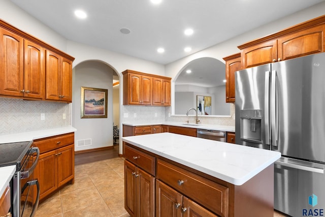 kitchen with tasteful backsplash, stainless steel appliances, arched walkways, and a sink