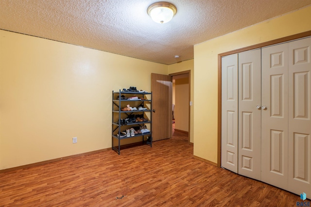 bedroom with wood finished floors, a textured ceiling, and a closet