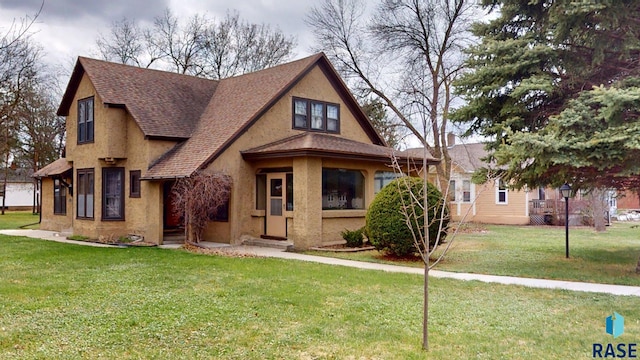 712 6th St, Brookings, SD 57006 - view of front of house featuring a front lawn, stucco siding, and roof with shingles