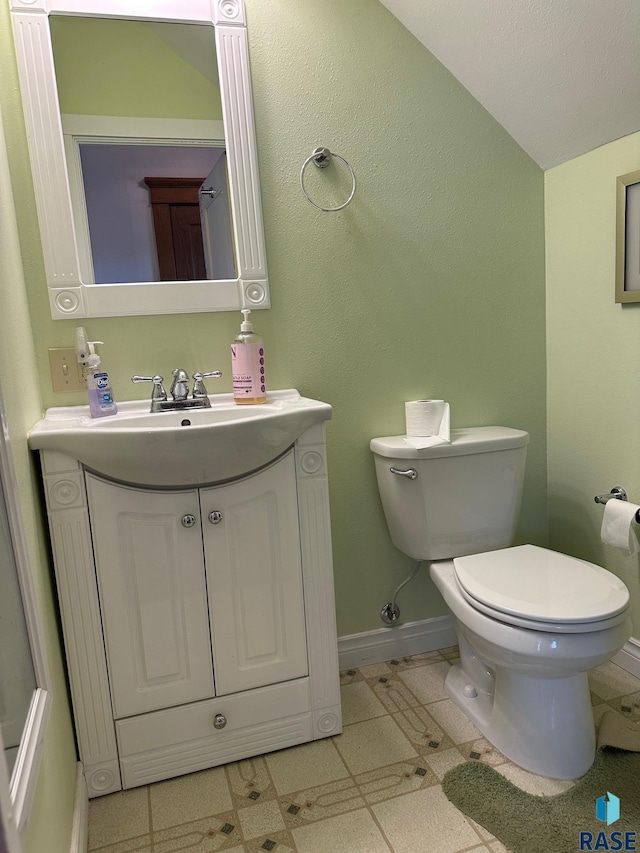 712 6th St, Brookings, SD 57006 - half bathroom with vanity, toilet, vaulted ceiling, and baseboards