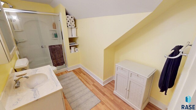712 6th St, Brookings, SD 57006 - bathroom featuring wood finished floors, lofted ceiling, a stall shower, and vanity