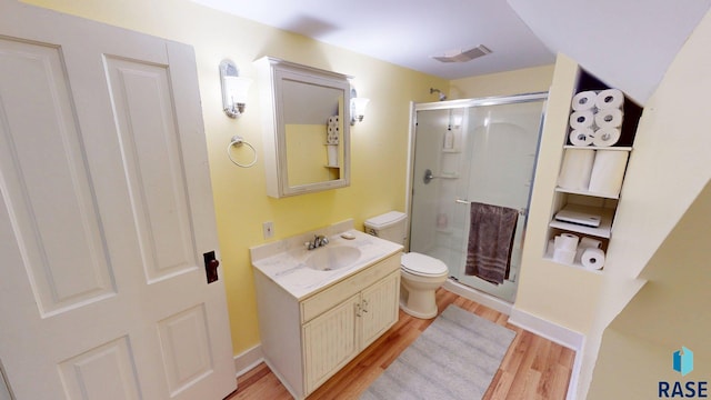 712 6th St, Brookings, SD 57006 - full bath with visible vents, a stall shower, toilet, wood finished floors, and vanity