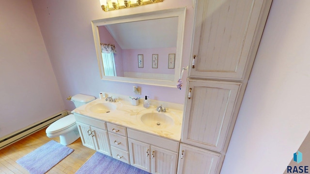 712 6th St, Brookings, SD 57006 - bathroom with toilet, a baseboard heating unit, a sink, and vaulted ceiling