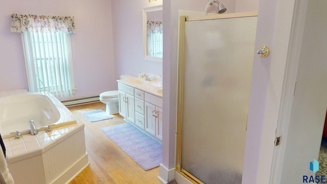 712 6th St, Brookings, SD 57006 - full bathroom with a baseboard heating unit, vanity, a stall shower, a garden tub, and wood finished floors