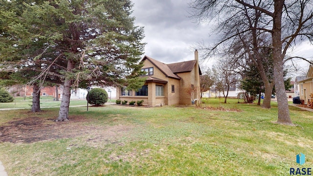 712 6th St, Brookings, SD 57006 - view of front of house with a front lawn, stucco siding, and a chimney