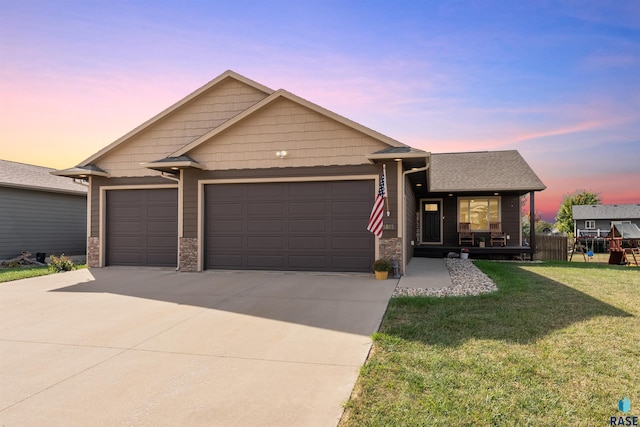 ranch-style house featuring a yard, covered porch, driveway, stone siding, and an attached garage