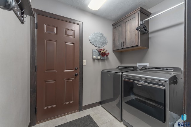 laundry area featuring cabinet space, light tile patterned floors, separate washer and dryer, baseboards, and a textured ceiling