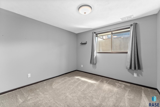 carpeted spare room with visible vents and baseboards