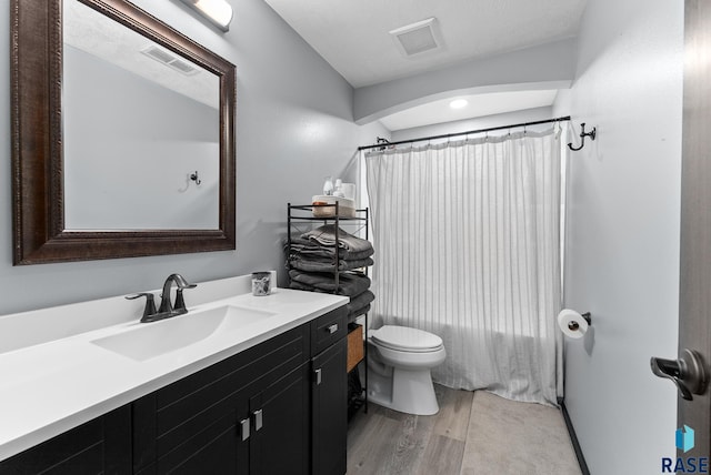 bathroom featuring toilet, vanity, visible vents, and wood finished floors