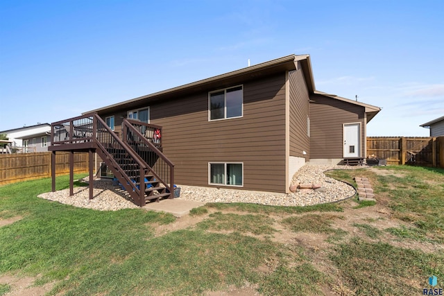 rear view of house with a deck, a fenced backyard, a yard, and stairs