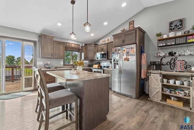 kitchen featuring light wood finished floors, lofted ceiling, stainless steel appliances, and light countertops