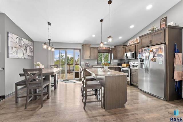 kitchen featuring a center island, wood finished floors, vaulted ceiling, and stainless steel appliances