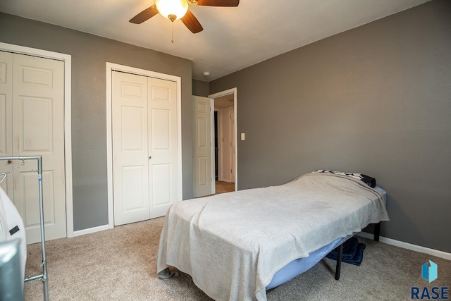carpeted bedroom with baseboards, a ceiling fan, and two closets