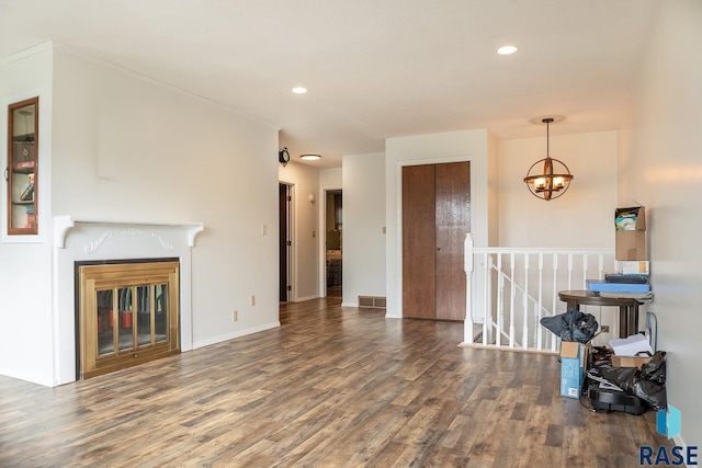 living area with visible vents, a glass covered fireplace, wood finished floors, recessed lighting, and a notable chandelier