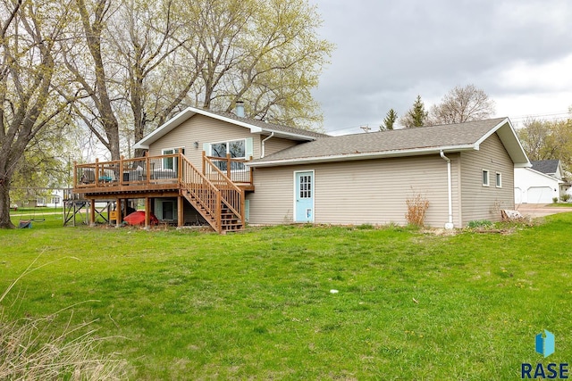 rear view of property with a lawn, roof with shingles, a deck, and stairway