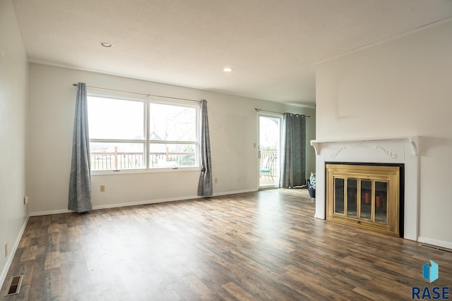 unfurnished living room featuring baseboards, visible vents, a glass covered fireplace, and wood finished floors