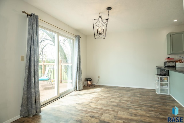 unfurnished dining area featuring baseboards, wood finished floors, and a chandelier