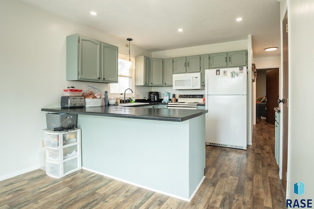 kitchen featuring a peninsula, dark countertops, white appliances, and dark wood-type flooring