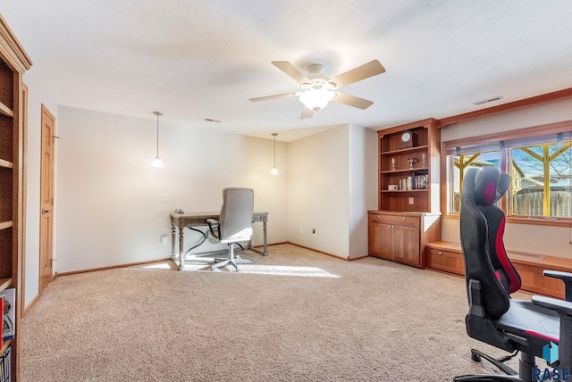 office featuring light colored carpet, visible vents, a ceiling fan, and baseboards