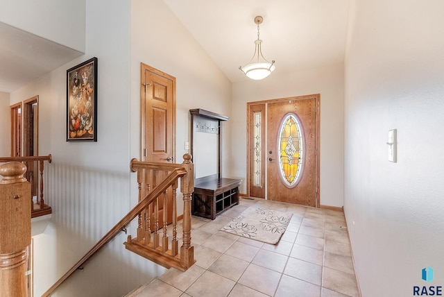 foyer with light tile patterned flooring, lofted ceiling, and baseboards