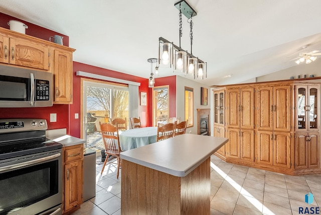 kitchen featuring stainless steel appliances, light tile patterned floors, light countertops, a center island, and lofted ceiling