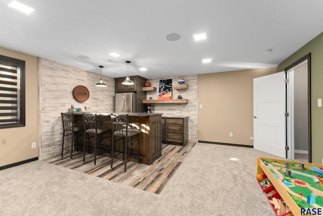 bar with wet bar, baseboards, light colored carpet, and freestanding refrigerator