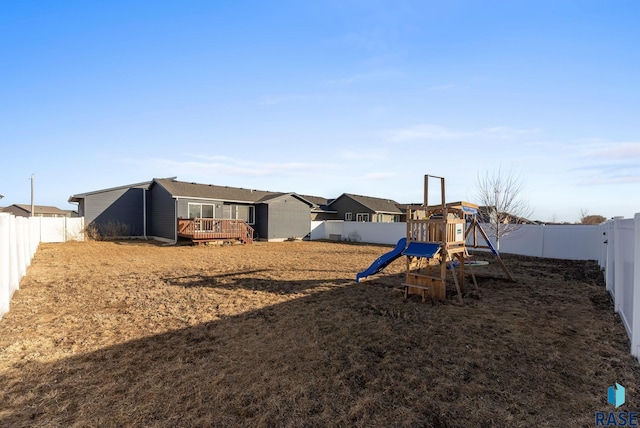 view of yard with a residential view, a deck, a playground, and a fenced backyard