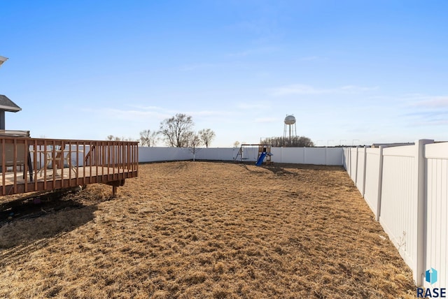 view of yard with a deck, a playground, and a fenced backyard