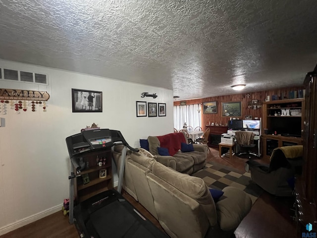 living area with a textured ceiling, wood finished floors, visible vents, and baseboards