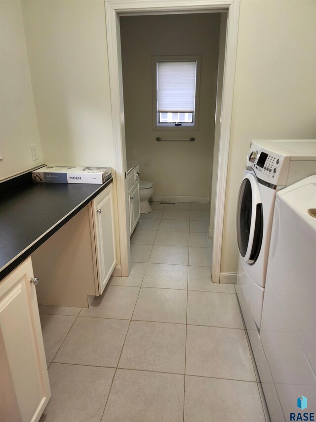 laundry area featuring light tile patterned floors, baseboards, laundry area, and washer and clothes dryer