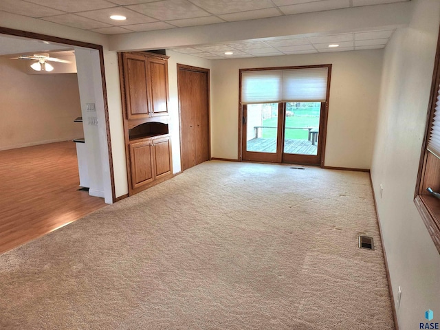 unfurnished room featuring light colored carpet, a drop ceiling, baseboards, visible vents, and a ceiling fan