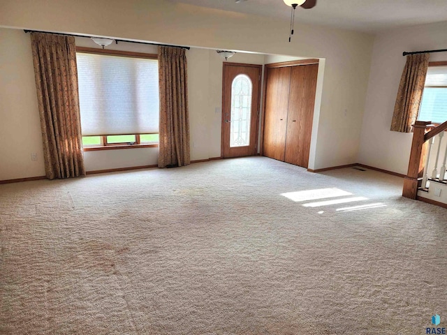 carpeted spare room with baseboards, a healthy amount of sunlight, and ceiling fan