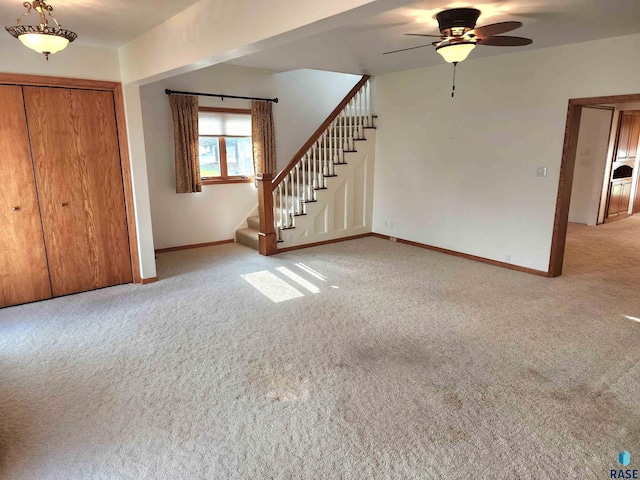 entrance foyer with baseboards, stairway, ceiling fan, and light colored carpet