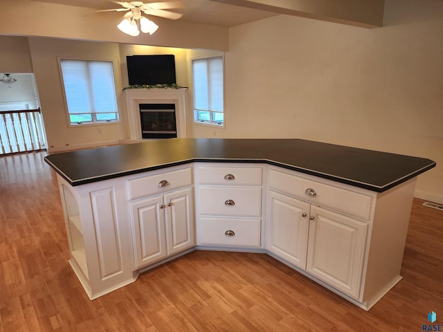 kitchen featuring a wealth of natural light, dark countertops, ceiling fan, light wood finished floors, and open floor plan