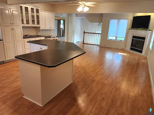 kitchen with dark countertops, ceiling fan, light wood-style flooring, and a center island