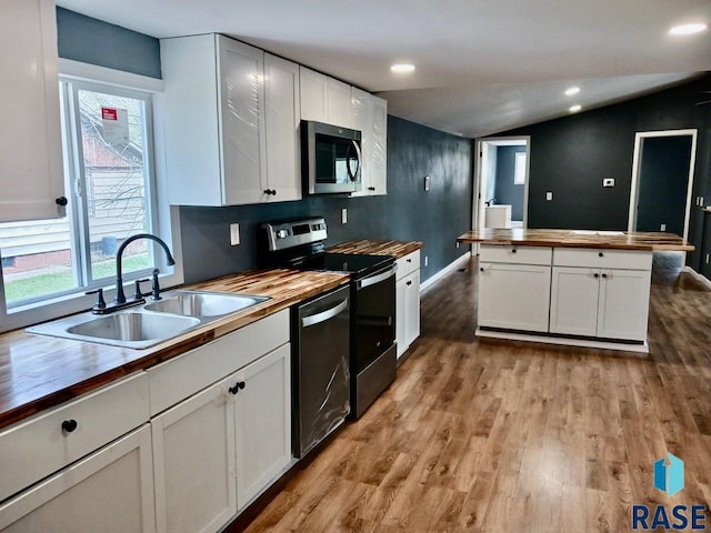 kitchen featuring lofted ceiling, a sink, stainless steel appliances, plenty of natural light, and butcher block countertops