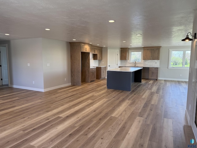 301 W 2nd St, Marion, SD 57043 - kitchen featuring light wood-style floors, a kitchen island, baseboards, recessed lighting, and backsplash