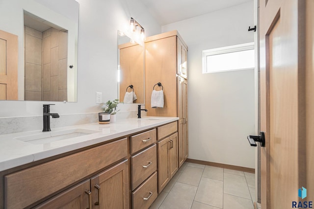 full bathroom with double vanity, baseboards, tile patterned flooring, and a sink