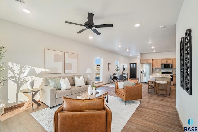 living room featuring baseboards, recessed lighting, ceiling fan, and light wood-style floors