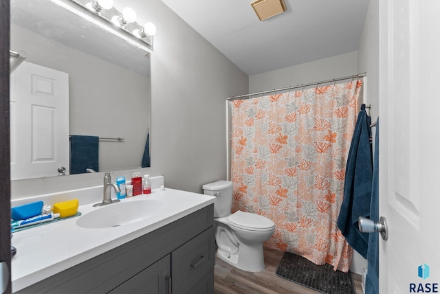 bathroom featuring toilet, vanity, curtained shower, and wood finished floors