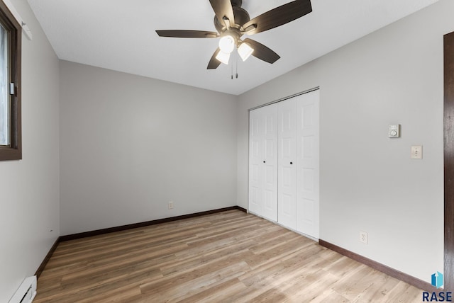 unfurnished bedroom featuring a closet, baseboards, wood finished floors, and a baseboard radiator