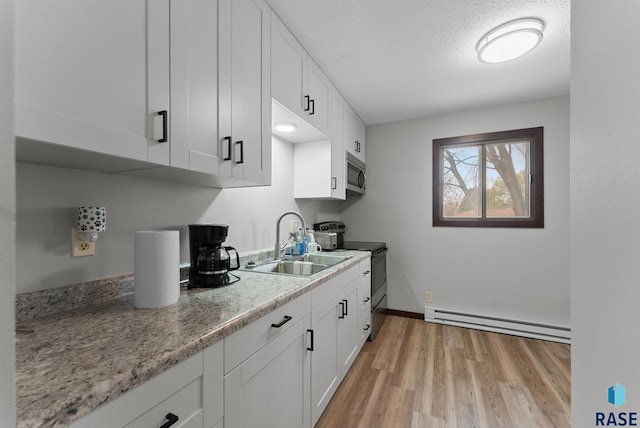 kitchen with a sink, stainless steel appliances, light wood-style floors, white cabinetry, and a baseboard radiator