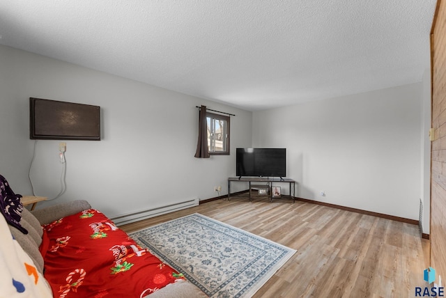 living area featuring a baseboard heating unit, a textured ceiling, wood finished floors, and baseboards